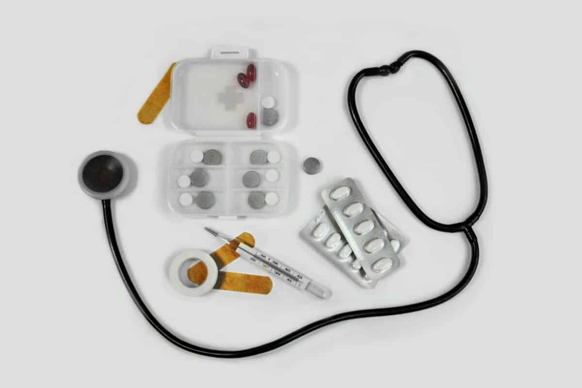 pill case with pills, bandaids, and stethoscope on white background