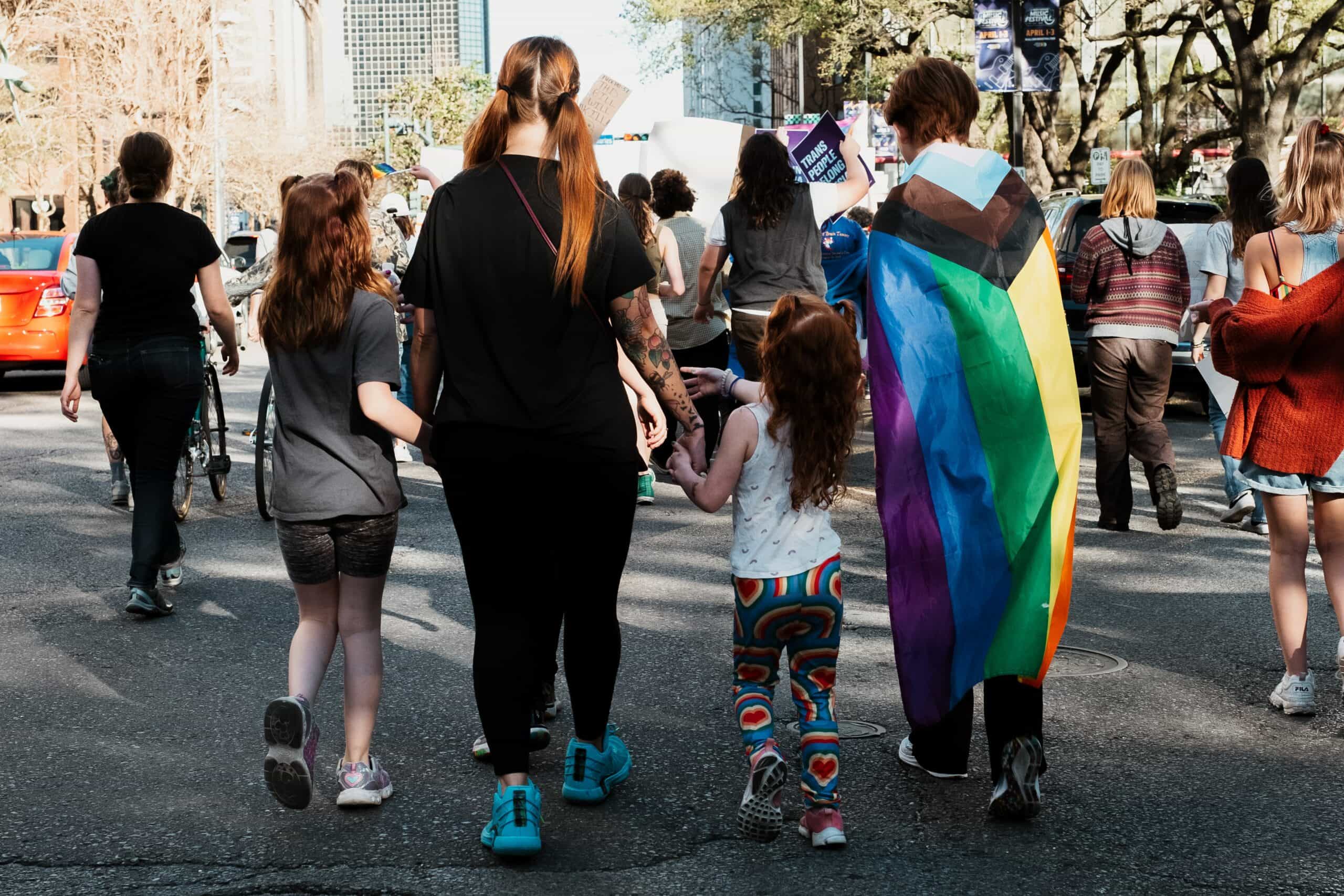 Link to Courses page. Description: family of four at Pride march.